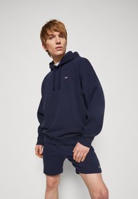 Tums zilsgans hoodie ar aukliņu, ribotām piedurknēm un logotipa detaļu uz krūšu, saskaņots ar atbilstošām šortiem, izgatavots no gluda kokvilnas auduma.