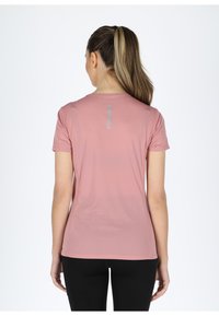 Light pink athletic t-shirt with short sleeves, round neckline, and horizontal texture; features a reflective strip on the back.