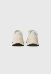 Lightweight athletic shoes in white and beige. Features a smooth upper, plush heel, and textured sole with a black tread pattern.