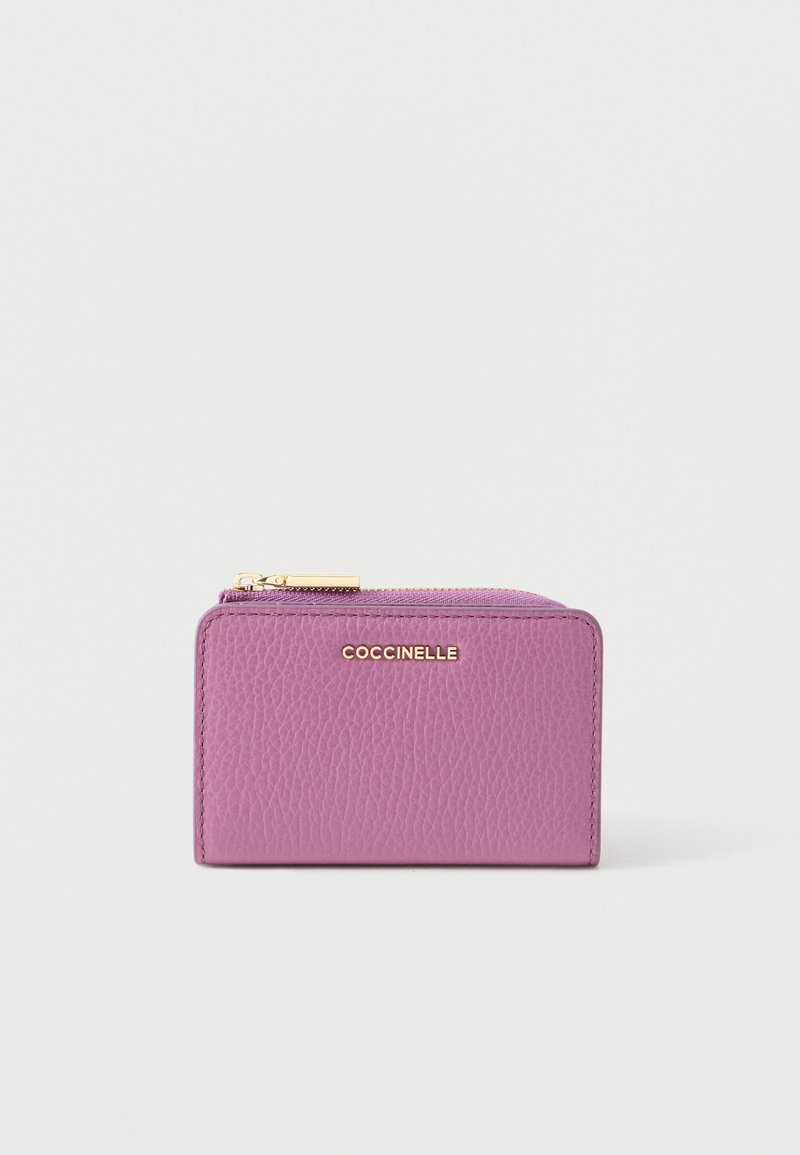 Violetti nahkainen lompakko, jossa teksturoitu pinta, vetoketjusuljenta ja kultainen logoyksityiskohta. Suorakulmainen muoto, kompakti design.