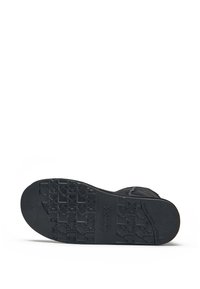 Suela de zapato negra con patrón texturizado. Presenta una forma plana, material de goma con logo de la marca en relieve y un borde resistente.