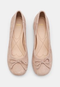 Ballet apavi maigi bēšā zamšā ar noapaļotu purngalu, smalku loku detaļu un mīkstu iekšējo zoli ar sirds formas šuvēm.