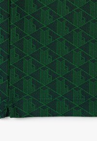Tissu vert à motifs avec un design géométrique composé de formes imbriquées et de rayures verticales, créant une apparence texturée et stratifiée.