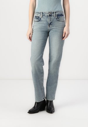 Lyseblå denimjeans med rett ben-design, fem lommer og subtil fading. Kombinert med svarte hæler for kontrast.