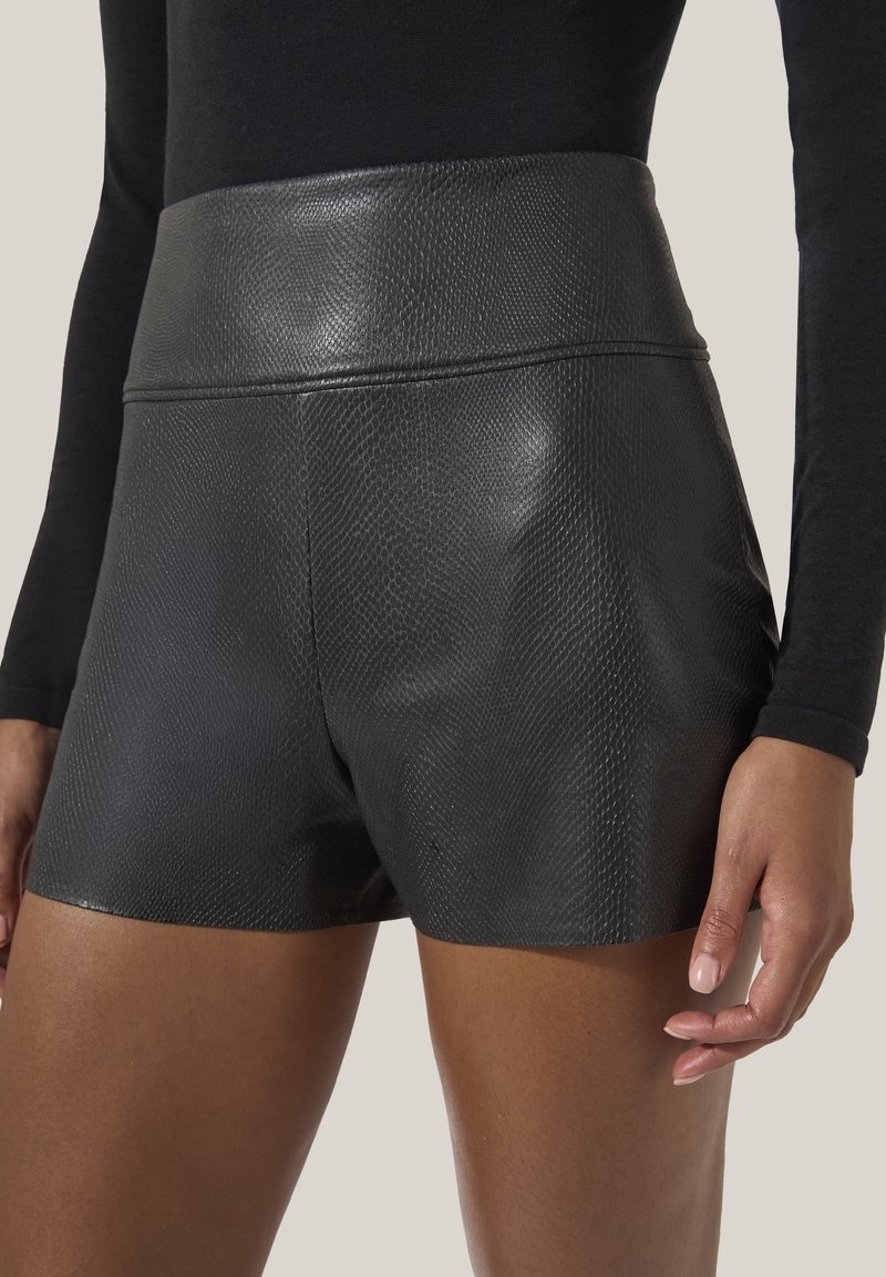 Höga svarta shorts tillverkade av ett texturerat läderliknande material, med en slät yta och en figurnära siluett.
