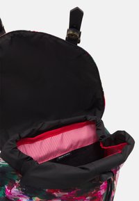 Värikäs kukkakuvioinen kangaskassi mustalla vuorella, punavalkoraidallisella vuorauksella ja nahkaosilla sulkemisessa.