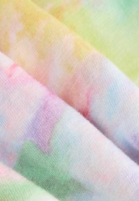 Soft fabric with a pastel tie-dye pattern in light pink, green, yellow, and blue shades, showing detailed woven texture and gentle folds.
