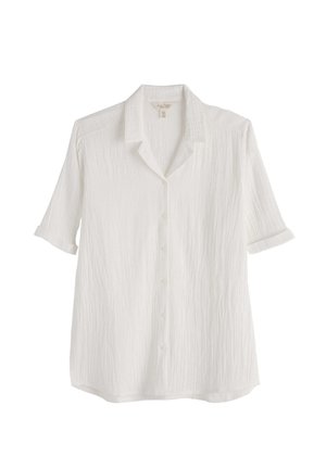 Fehér rövid ujjú, gombos ing texturált anyaggal és puha gallérral, egyszerű háttéren bemutatva.