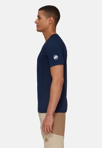 Marineblauwe shirt met korte mouwen, slim fit, gemaakt van vochtafvoerende stof, met een logopatch op de linker mouw en naaddetails.