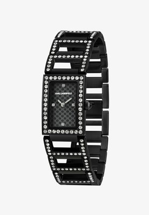 Montre rectangulaire noire avec un cadran à motif en fibre de carbone, entouré de cristaux clairs et un bracelet à maillons géométriques.