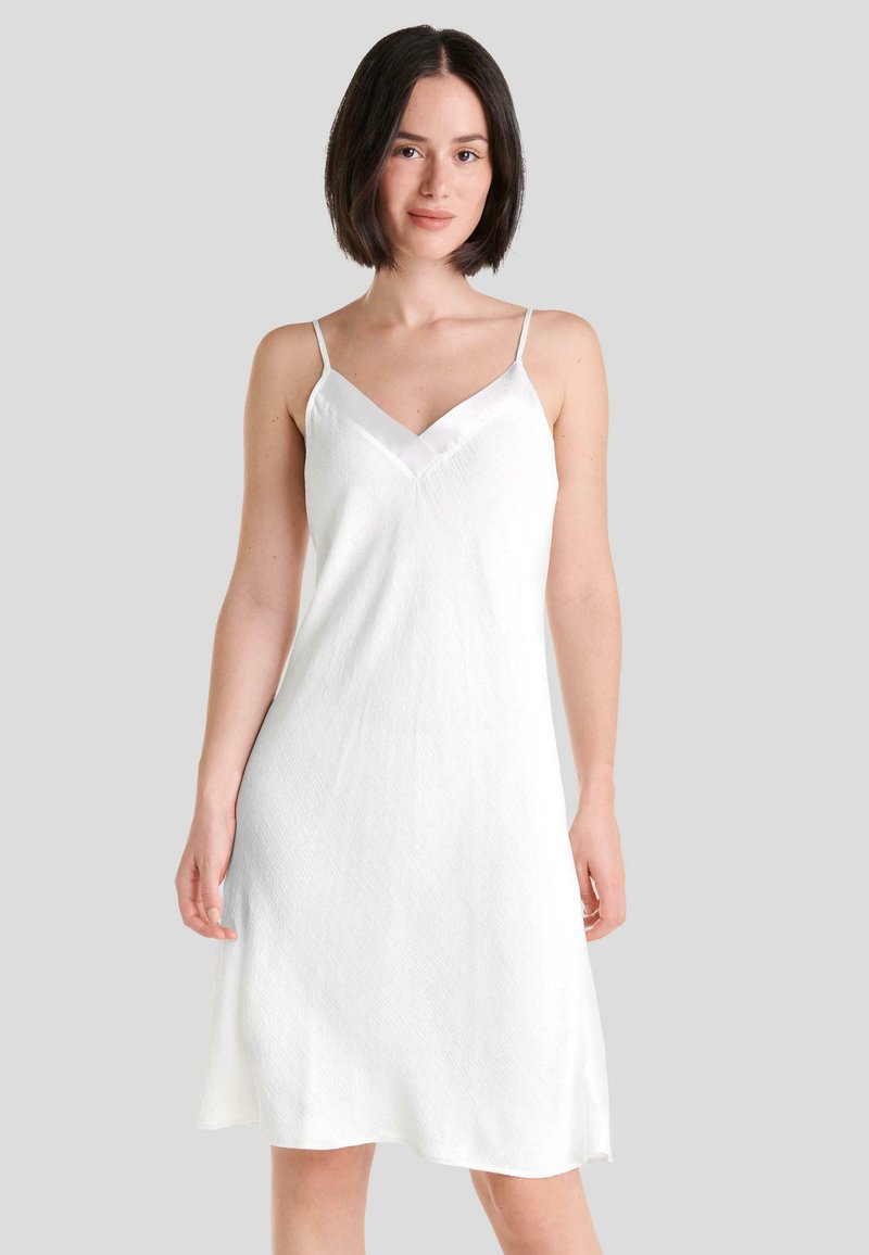 Vestido blanco sin mangas con escote en V, hecho de una tela texturizada, que presenta tirantes finos y una silueta recta y fluida.
