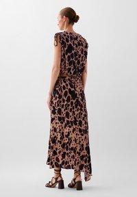 Robe maxi imprimée animal en beige et noir, avec des manches courtes, une coupe décontractée et un nœud à la taille. Sandales à talons blocs noires à brides.
