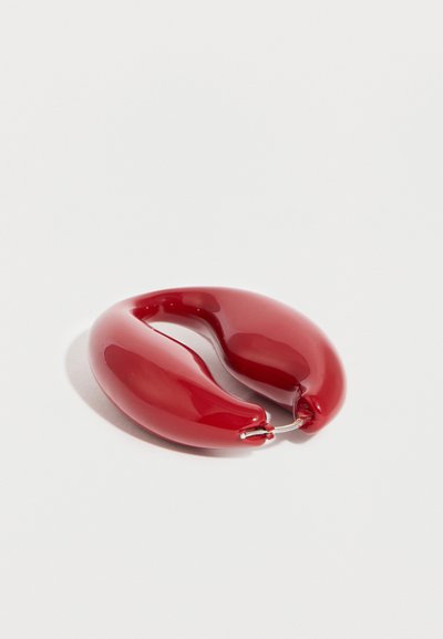 Γυαλιστερό κόκκινο κρίκο σκουλαρίκι με στρογγυλεμένο, χοντρό σχήμα και μεταλλικό κούμπωμα σε λευκό φόντο.