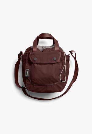 Compact dark brown shoulder bag with front flap pocket, dual handles, adjustable strap, and visible drawstring closure on top.