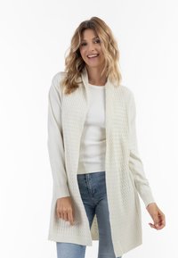 Knælang cremedfarvet cardigan med tekstureret front, åben forkant, ribbede manchetter og en let A-formet silhuet.