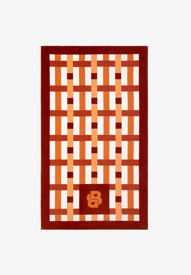 Tapis avec un motif en grille tissé rouge et orange et un carré avec les lettres stylisées « BB » près du centre en bas.