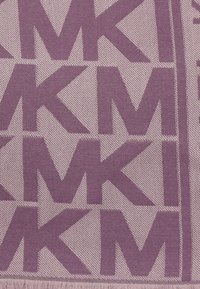 Lilla vævet stof med et gentaget "MK" mønster, med en struktureret finish og frynset kant.