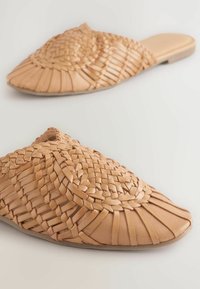Chaussures en cuir tressé couleur sable, à enfiler, avec un bout rond, présentant un design tressé et une semelle plate pour le confort. Texture légère et flexible.