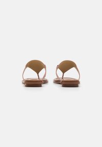 Sandale din piele roz cu curea la spate, talpă plată maro și design minimalist. Dispune de detalii cu curea între degete.