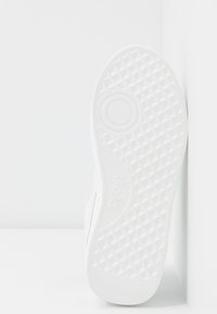 Sola di sneaker bianca con motivo a diamante e accentuazione circolare. Presenta bordi lisci e logo del brand stampato in rilievo. Design pulito e funzionale.