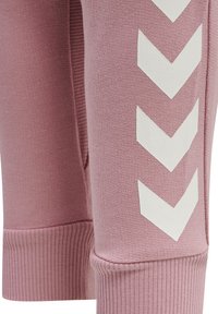 Rosa mjukisbyxor i mjukt tyg med vita chevronmönster på sidan och ribbade muddar i botten som ger en snug passform.