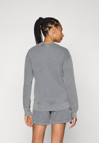 Grå ribbet sweatshirt med lange ermer og rund hals, kombinert med matchende grå shorts. Teksturert stoff, uformelt design, avslappet passform.