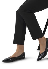 Zwarte gepatineerde leren ballerina's met een spitse neus en versieringen van kleine zilveren studs langs de randen. Gecombineerd met cropped zwarte broeken.