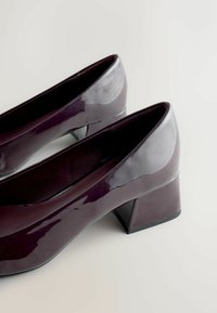 Kergelt läikivad tumepunased patend naha kõrged kontsad, millel on kontrastne matistatud must alus. Sile tekstuur ja voolujooneline disain.