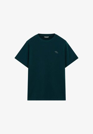 Camiseta de algodón verde oscuro, manga corta, cuello redondo, con un pequeño logo blanco bordado en el pecho. Textura suave, ajuste relajado.