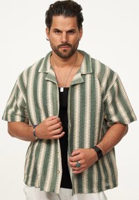 Kurzarmhemd mit gestreiftem Muster in Grün und Creme, gestrickter Textur, Knopfverschluss und Kragen-Design.