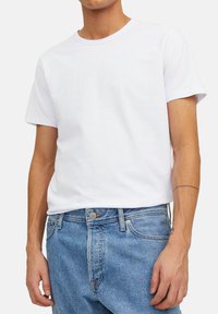 Witte katoenen t-shirt met een ronde hals en korte mouwen, gecombineerd met lichtblauwe denim jeans met knoop- en ritsluiting.