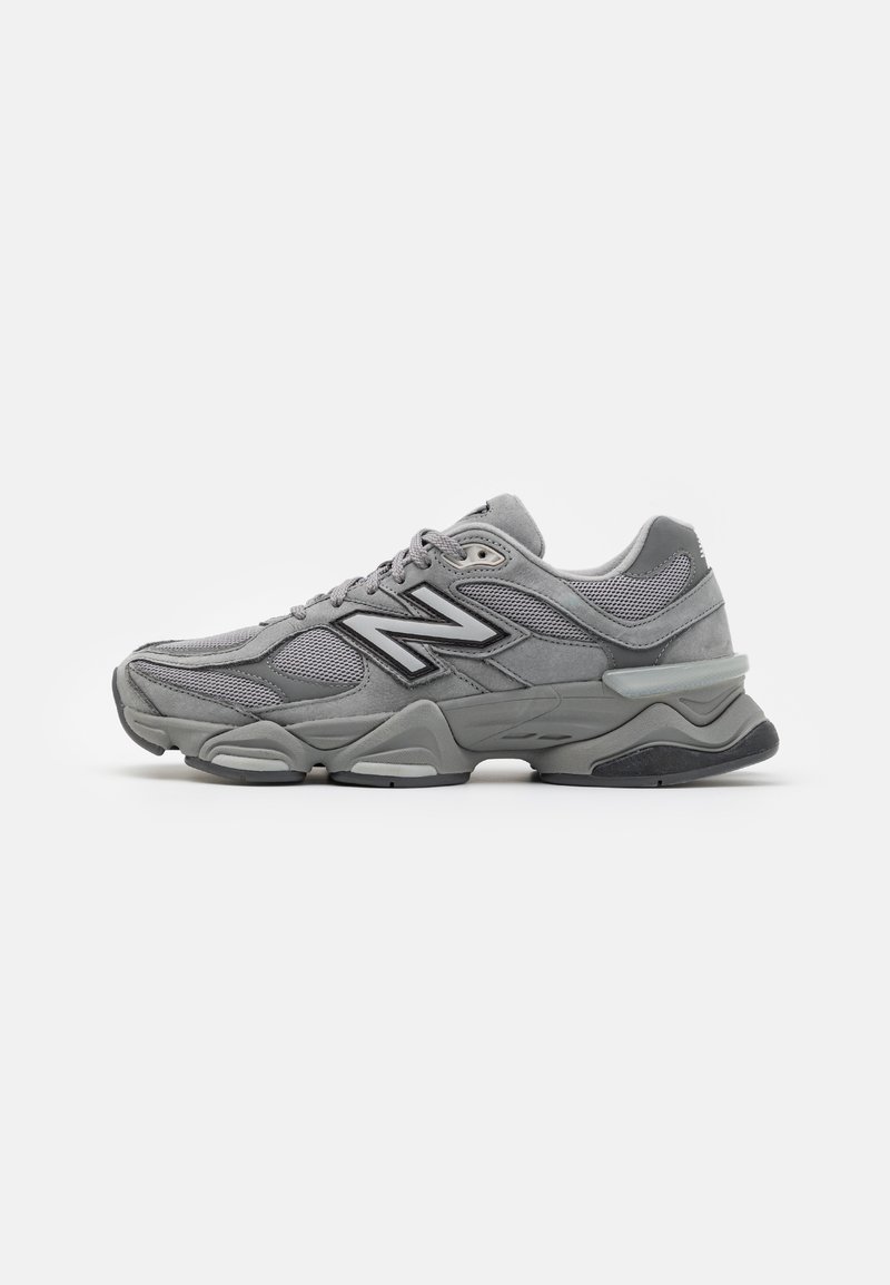 Baskets New Balance grises avec détails en mesh et suède, semelle épaisse et logo noir sur le côté, vues de profil sur fond blanc.