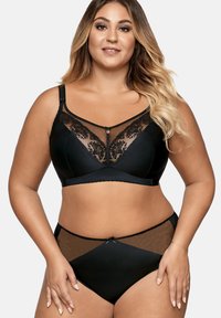 Ensemble de lingerie noir comprenant un bralette avec des panneaux en dentelle, des bretelles réglables et un petit bijou décoratif ; briefs taille haute assortis.