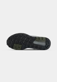 Schuhsohle mit einem schwarzen strukturierten Muster, das grüne Akzente und geometrische Profilierungen für besseren Halt aufweist. Hergestellt aus langlebigem Gummimaterial.