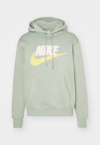 Ljusgrön bomullshuvtröja med en stor vit och gul Nike-logotyp, framsidig känguruficka och justerbar huva. Mjuk textur, ribbade ärmslut.