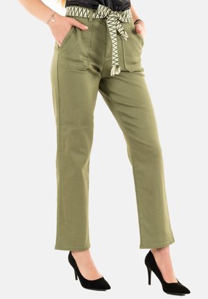 Pantaloni di cotone verdi con vita aderente, due tasche frontali e una cintura a fantasia. Abbinati a scarpe con tacco alto nere.