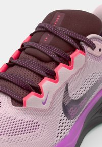 Zapatillas moradas claras con acentos morados oscuros, parte superior de malla texturizada, detalles en rosa y un destacado logo de swoosh en el lateral.