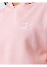 Lichtroze hoodie met een zachte textuur, voorzien van een geborduurd wit logo met de tekst "PXP" aan de linkerkant.