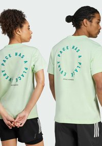 Light green cotton t-shirts feature a circular print on the back that reads "EVERY PACE HAS A PLACE" in dark teal. Short sleeves and relaxed fit.