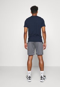 Marinblå t-shirt med kort ärm i kombination med gråa träningsshorts. Outfiten har en avslappnad passform och mjukt tyg, perfekt för avslappnad användning.