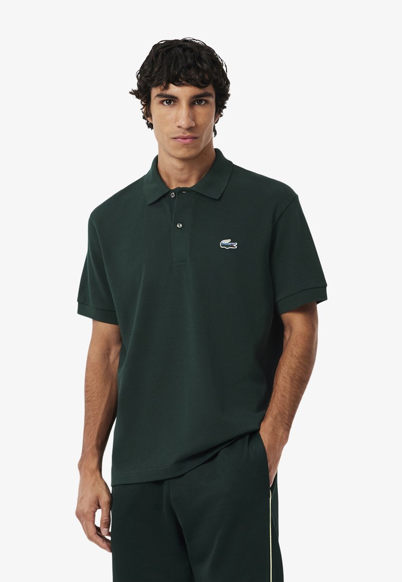 Donkergroen poloshirt gemaakt van katoen, met een klassieke kraag, een twee-knopen sluiting en een klein Lacoste-logo op de borst.