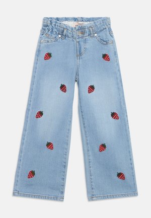 Jasnoniebieskie dziecięce spodnie dżinsowe z elastycznym paskiem, zapięciem na guzik oraz czerwonymi haftowanymi wzorami truskawek rozrzuconymi na przednich nogawkach.