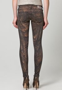 Slitna bruna skinny jeans med en texturerad, marmorerad mönster, med bakfickor och midjehöjd, matchat med högklackade skor.