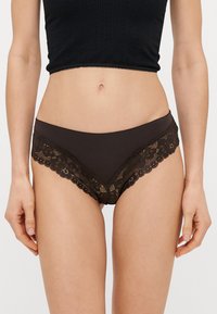 Culotte noire ornée de dentelle avec un motif floral, un corps en coton lisse et un bord festonné, conçue dans une coupe bikini classique.