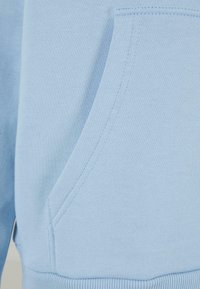 Svijetloplavi dukserica s kenguruvu džepom, rebrastim rubom i glatkom, mekanom teksturom s urednim šavovima.