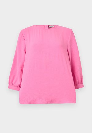 Felroze blouse met lange mouwen en een ronde hals, met een lichte textuur, voorzien van een ritssluiting aan de achterkant en manchetten aan de mouwen.