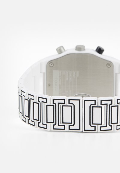 Hvidt ur med et mønstret rem, der har vekslende sorte geometriske former. Rustfrit stål bagpå med tre knapper og tekstureret overflade.