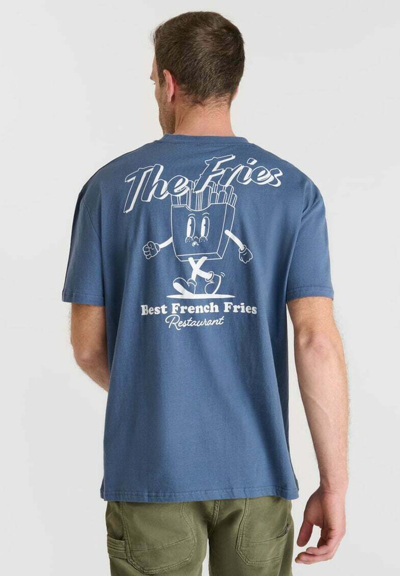 Hombre con una camiseta azul que tiene un personaje de patatas fritas de dibujos animados y el texto "El mejor restaurante de patatas fritas" en la parte de atrás.