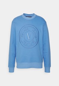Sweatshirt bleu clair à col rond avec des poignets et un ourlet côtelés, logo en relief de Versace Jeans Couture centré sur la poitrine.