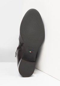 La semelle de chaussure en cuir noir présente une surface lisse avec une texture striée pour une meilleure adhérence. Le logo de la marque et le détail du drapeau italien sont visibles. Taille 37.